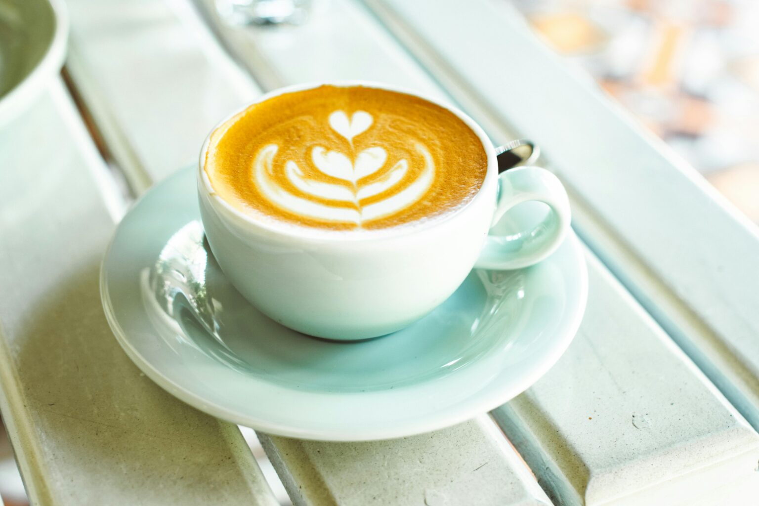 A cappuccino with heart-shaped latte art in a white cup on a table, perfect for coffee lovers.