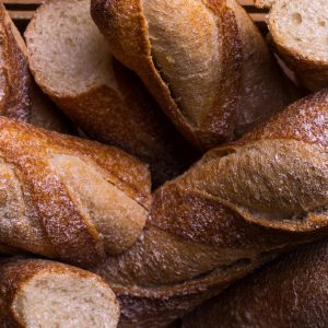 Rustic fresh baguettes in a basket, showcasing crusty textures and artisanal baking.