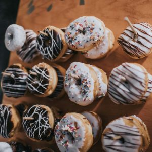 A variety of colorful, frosted donuts arranged on a wooden board for a tempting treat.